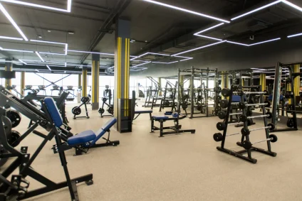 Sala fitness moderna e open space con attrezzatura variata, macchine, panche e specchi.